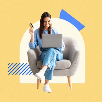 Woman seated on a chair, smiling with a laptop on her lap, holding a credit card
