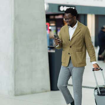 Business Professional Walking in Airport Terminal With Luggage