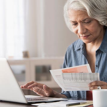 woman looking at bill and working on laptop