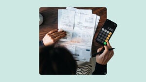 Above angle view of woman calculating bills on calculator