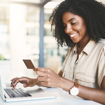 Shot of a young businesswoman using a credit card and laptop in a modern office