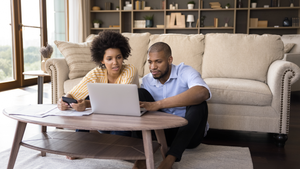 Couple at home working on their finances on their laptop in the living room.