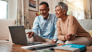 Mature couple sitting at a laptop, planning their finances.