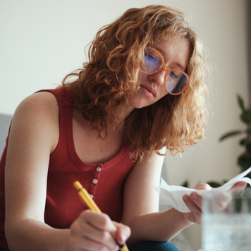Young woman calculating her finances while sitting with her laptop.