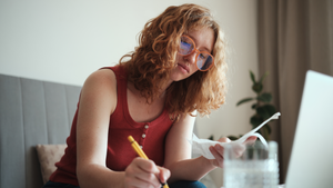 Young woman calculating her finances while sitting with her laptop.